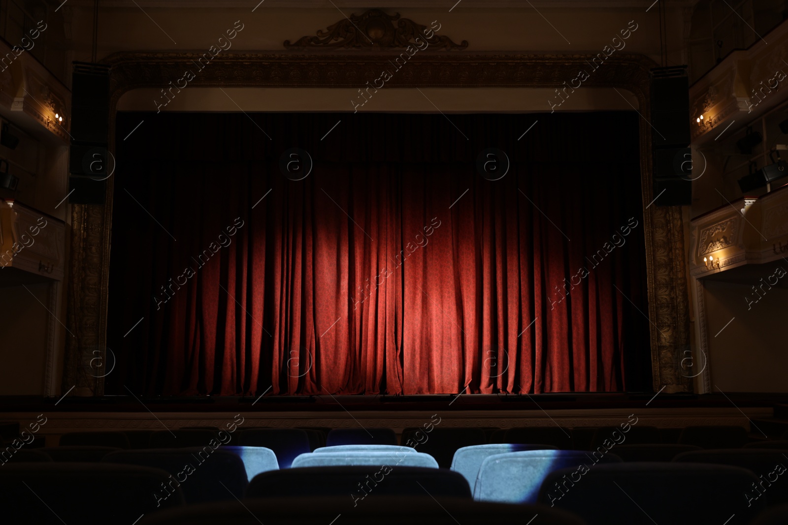 Photo of Elegant closed red curtains illuminated by spotlight in theatre