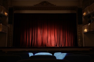 Photo of Elegant closed red curtains illuminated by spotlight in theatre