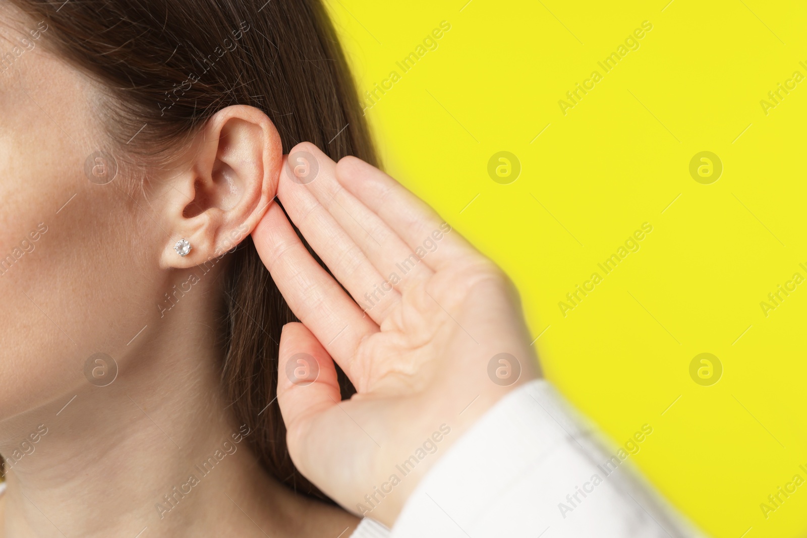 Photo of Woman showing hand to ear gesture on dark yellow background, closeup. Space for text