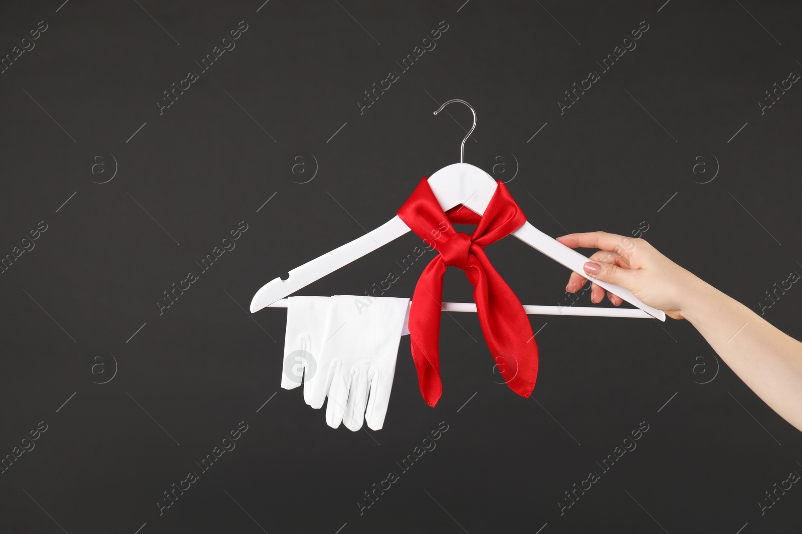 Photo of Woman holding hanger with red handkerchief and white gloves on black background, closeup. Space for text