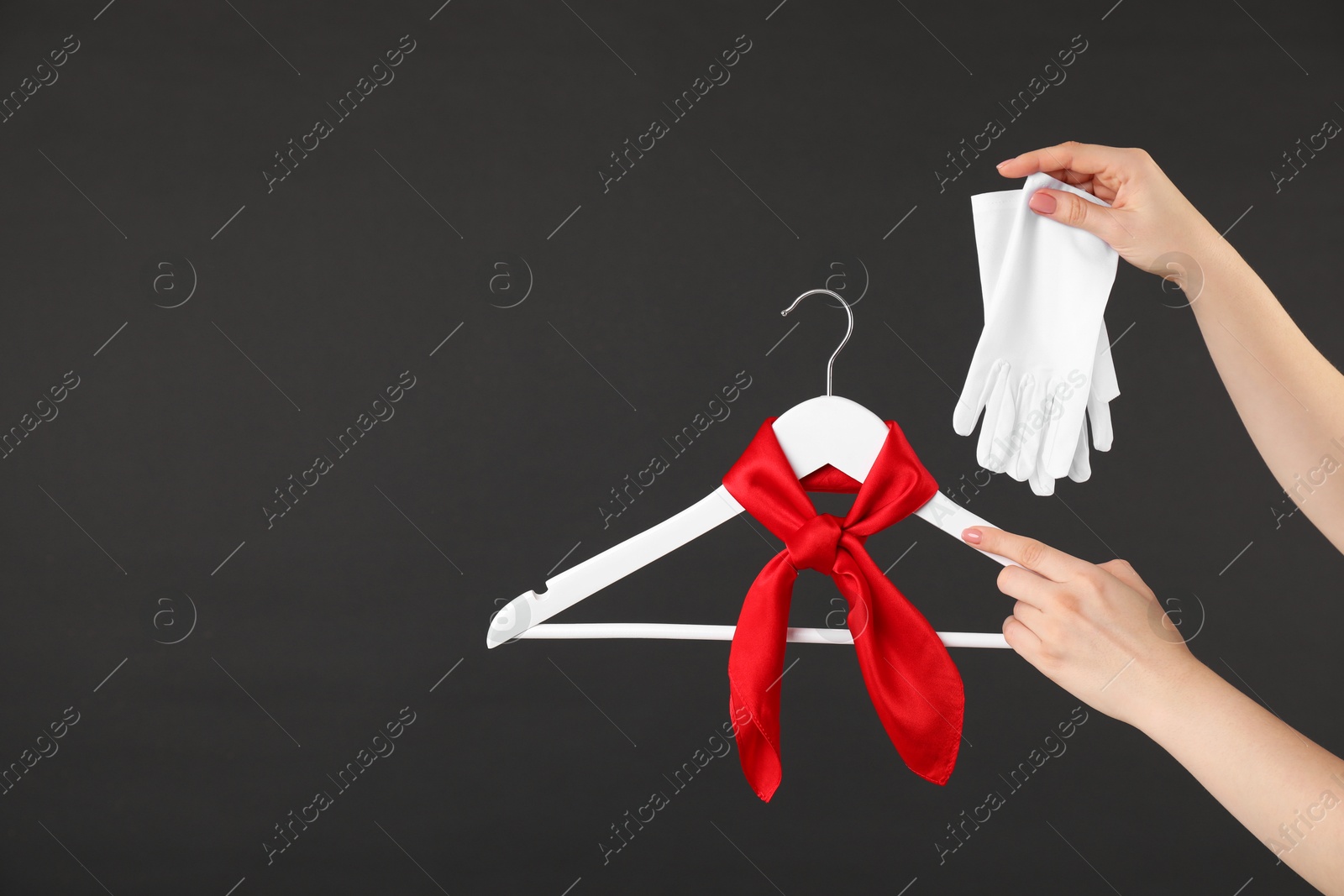 Photo of Woman holding hanger with red handkerchief and white gloves on black background, closeup. Space for text