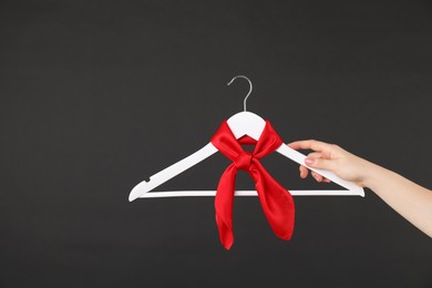 Photo of Woman holding hanger with red handkerchief on black background, closeup. Space for text