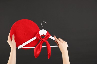 Photo of Woman holding hanger with red handkerchief on black background, closeup. Space for text