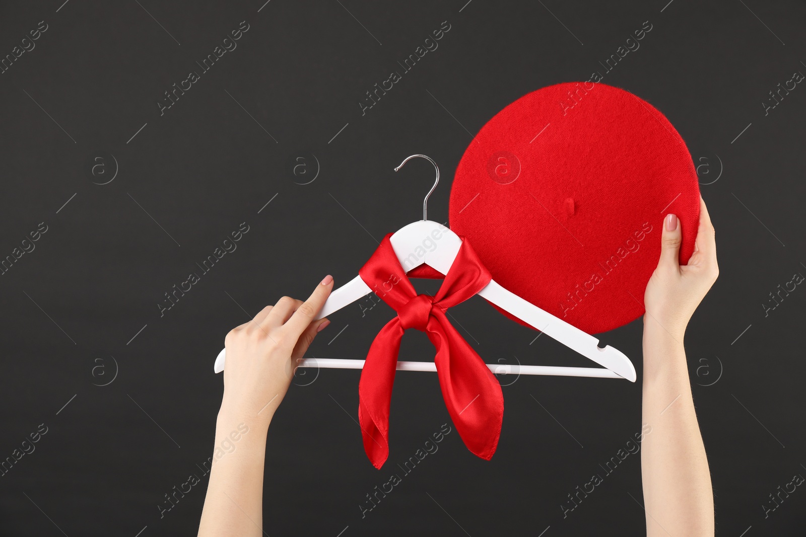 Photo of Woman holding hanger with red handkerchief on black background, closeup. Space for text