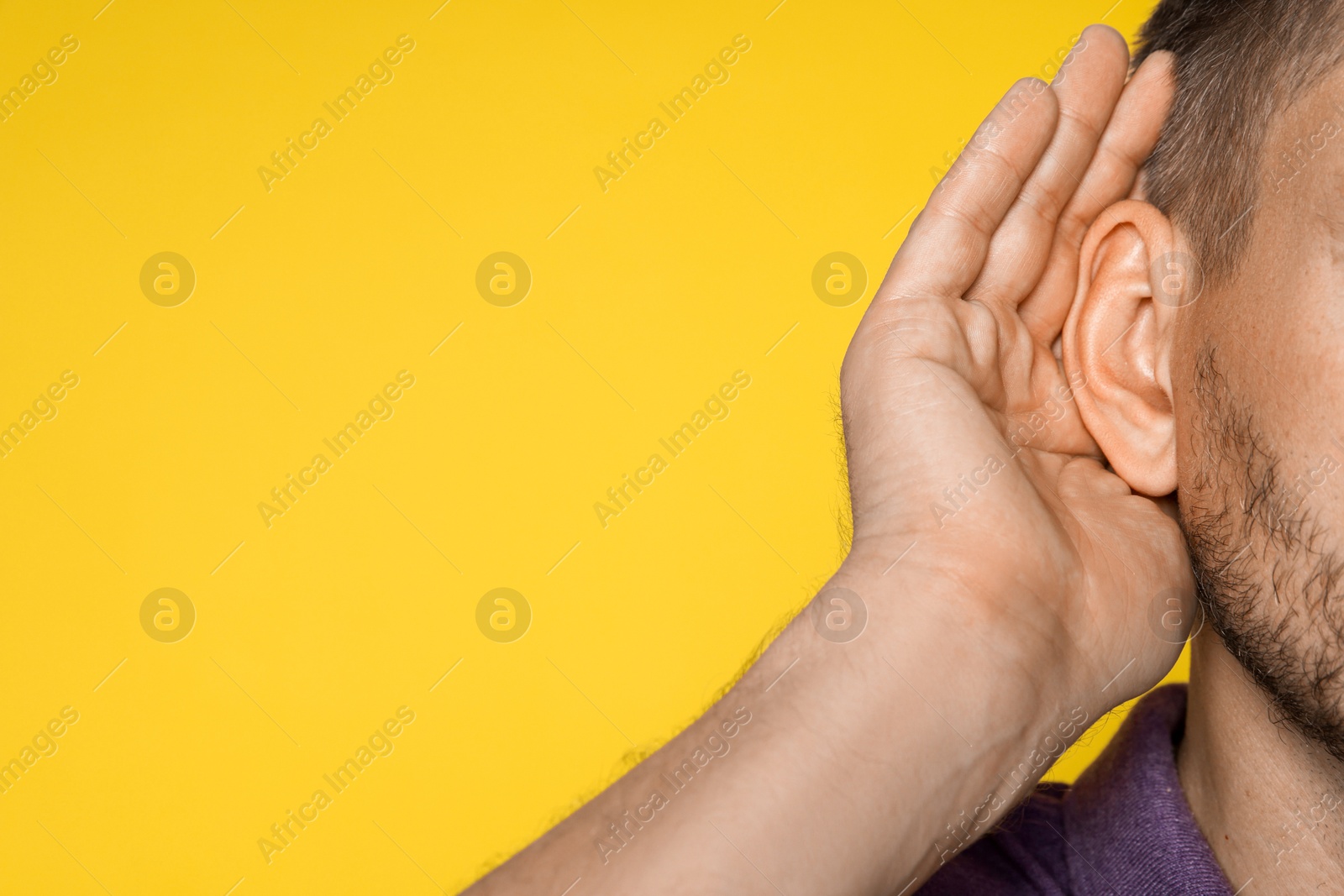 Photo of Man showing hand to ear gesture on orange background, closeup. Space for text