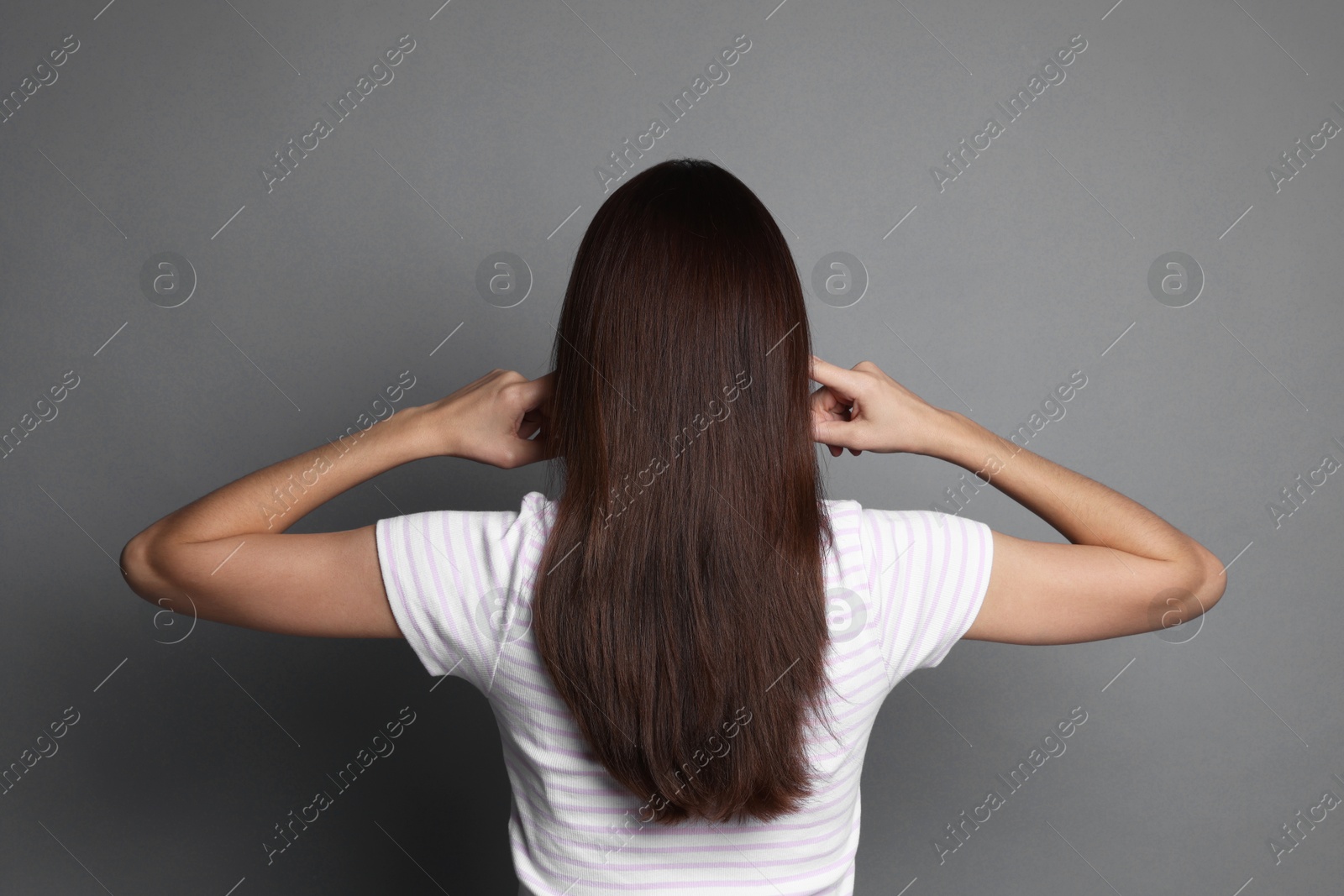 Photo of Woman covering her ears with fingers on grey background, back view