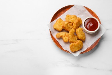 Photo of Delicious chicken nuggets and ketchup on white marble table, top view. Space for text