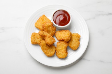 Photo of Delicious chicken nuggets and ketchup on white marble table, top view