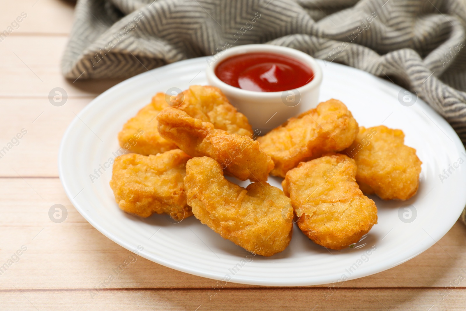 Photo of Delicious chicken nuggets and ketchup on wooden table, closeup