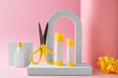 Photo of Composition with scissors and glue on light pink background