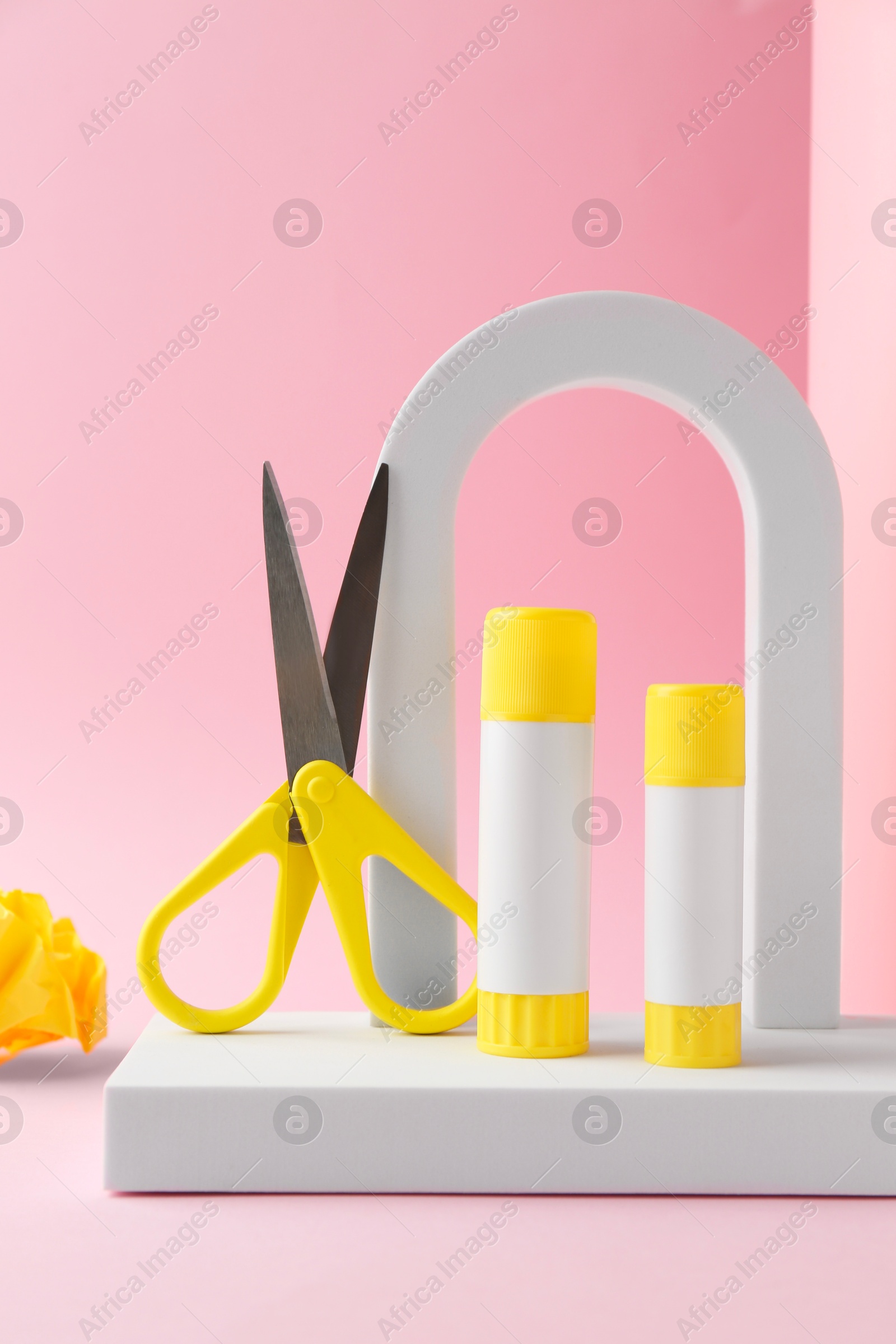 Photo of Composition with scissors and glue on light pink background