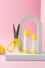 Photo of Composition with scissors and glue on light pink background