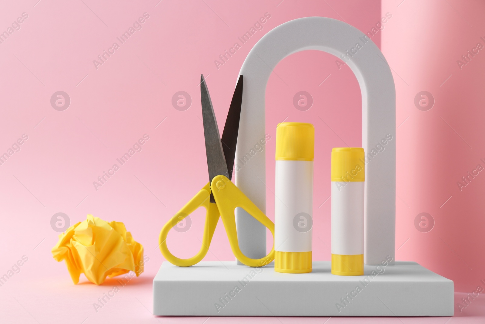 Photo of Composition with scissors and glue on light pink background