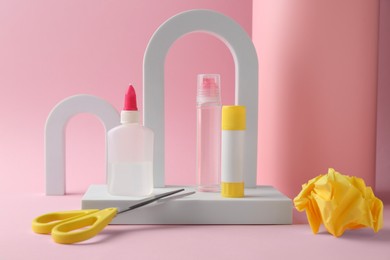 Photo of Composition with scissors and glue on light pink background