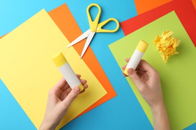 Photo of Woman with glue, scissors and colorful paper at table, top view