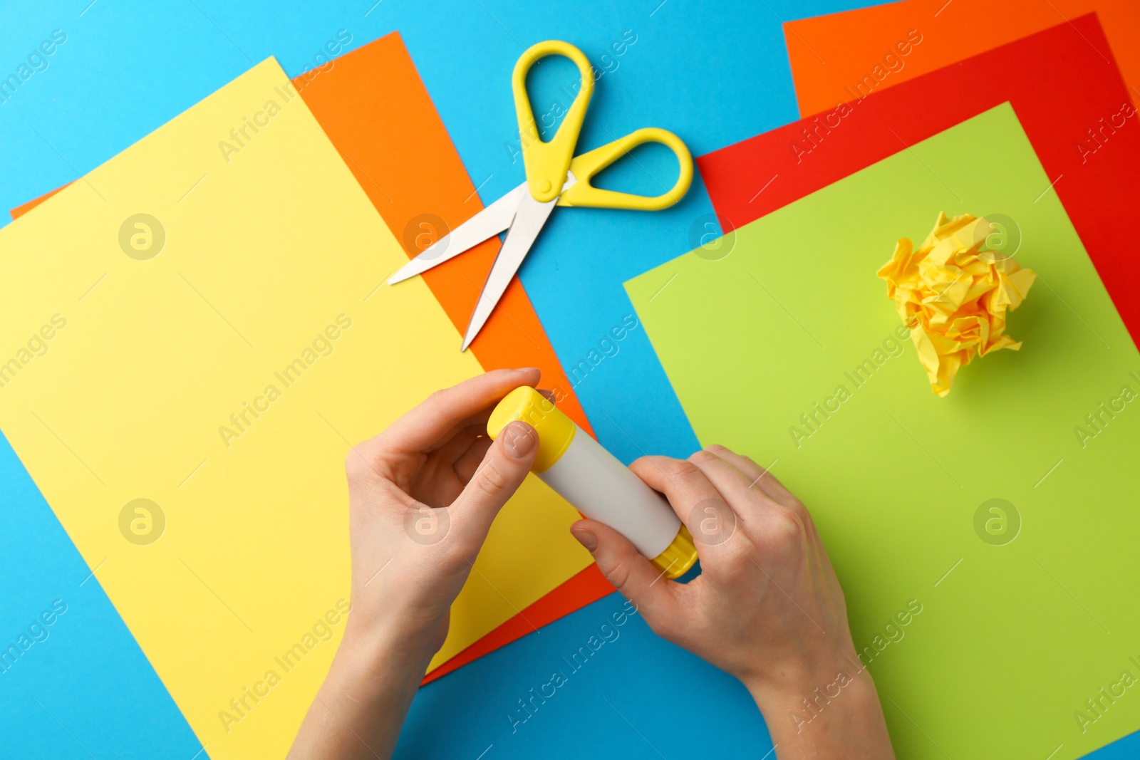 Photo of Woman with glue, scissors and colorful paper at table, top view