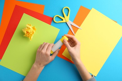 Photo of Woman with glue, scissors and colorful paper at table, top view