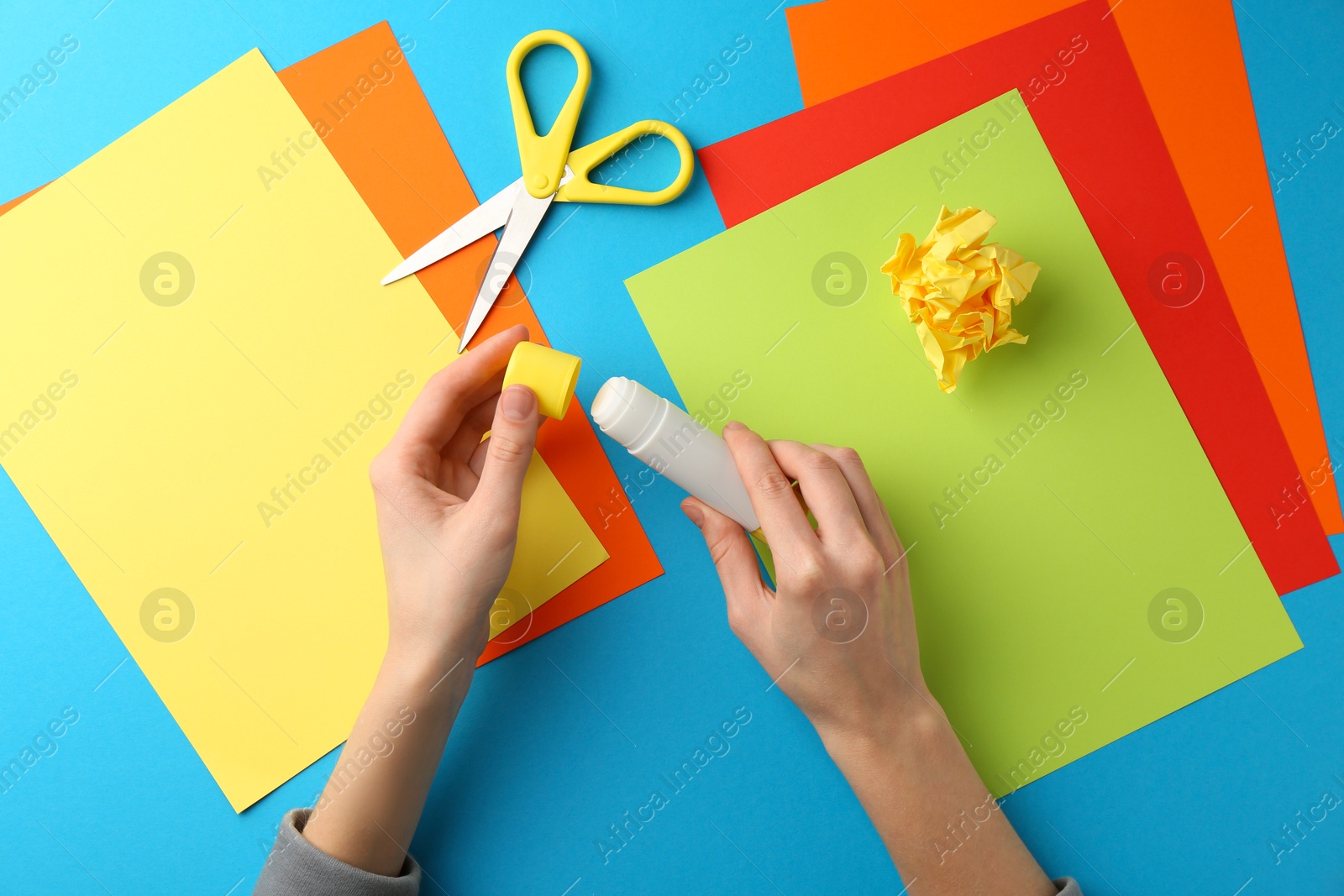 Photo of Woman with glue, scissors and colorful paper at table, top view