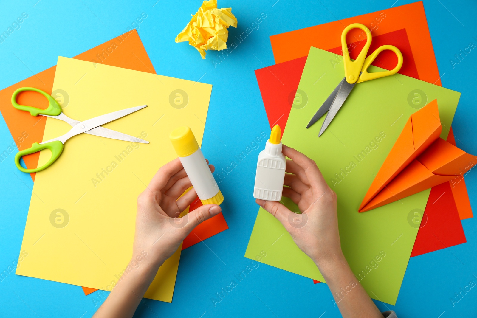 Photo of Woman with glue, scissors and colorful paper at table, top view