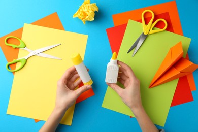 Photo of Woman with glue, scissors and colorful paper at table, top view