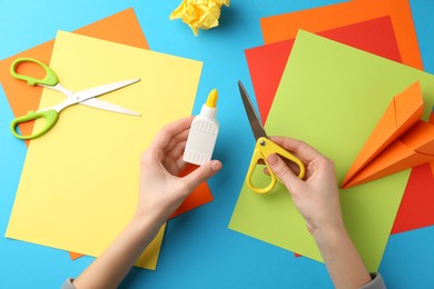 Photo of Woman with glue, scissors and colorful paper at table, top view