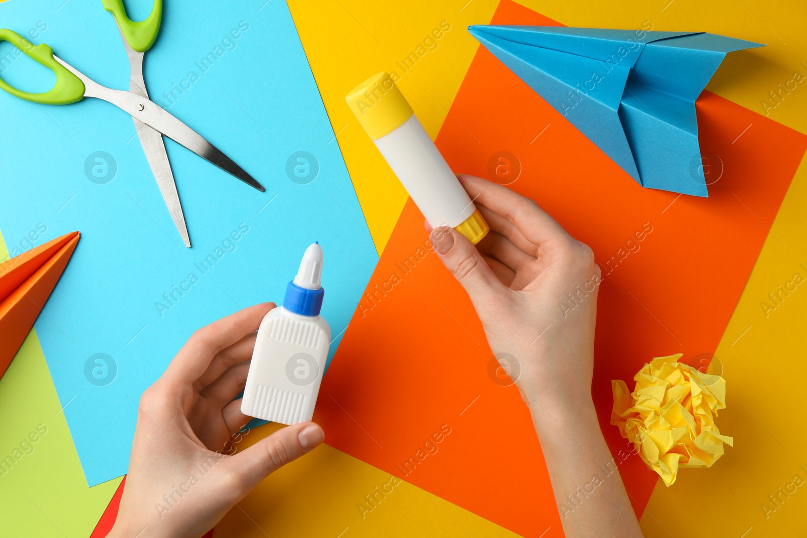 Photo of Woman with glue, scissors and colorful paper at table, top view