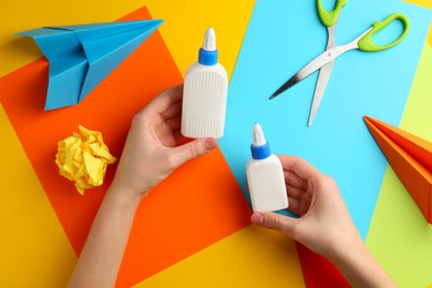 Photo of Woman with glue, scissors and colorful paper at table, top view