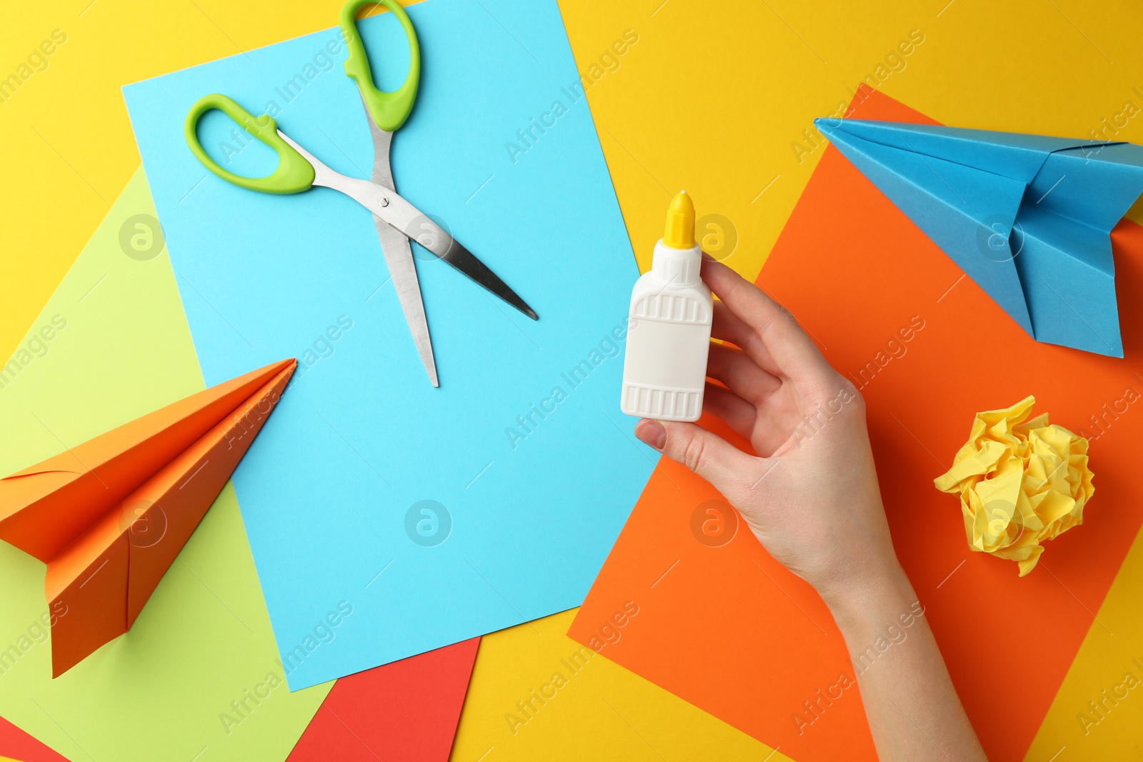 Photo of Woman with glue, scissors and colorful paper at table, top view