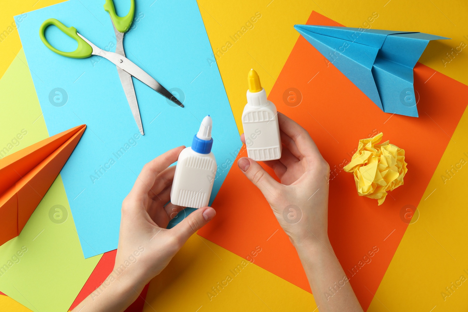 Photo of Woman with glue, scissors and colorful paper at table, top view