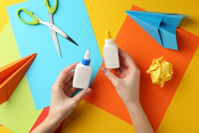 Photo of Woman with glue, scissors and colorful paper at table, top view