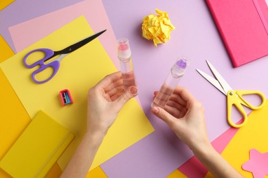 Photo of Woman with glue, scissors and colorful paper at table, top view