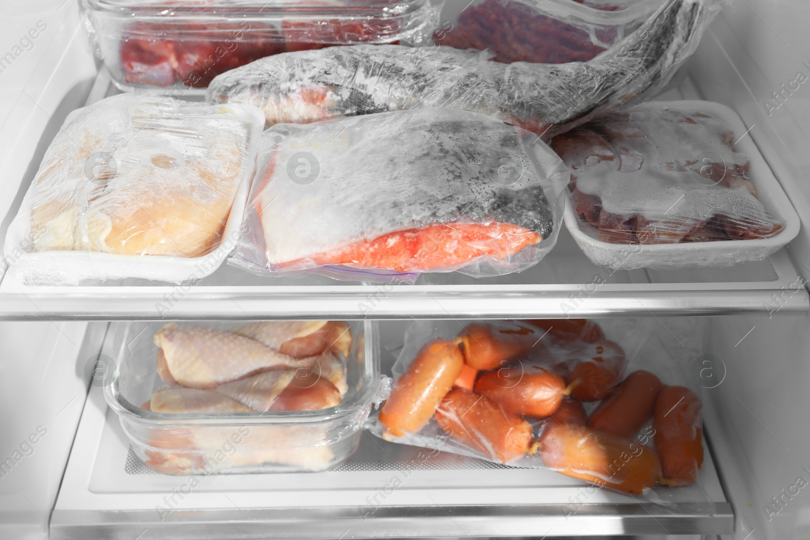 Photo of Different frozen meat and fish products in fridge, closeup