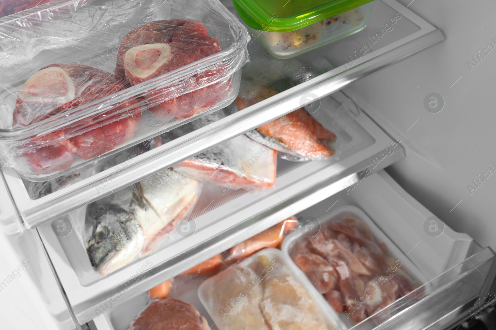 Photo of Different frozen meat and fish products in fridge, closeup