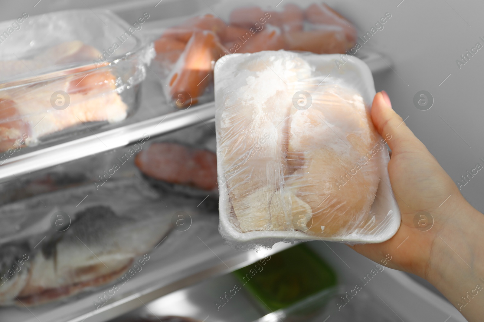 Photo of Woman taking frozen chicken breasts out of fridge, closeup