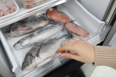 Photo of Woman taking frozen fish out of fridge, closeup