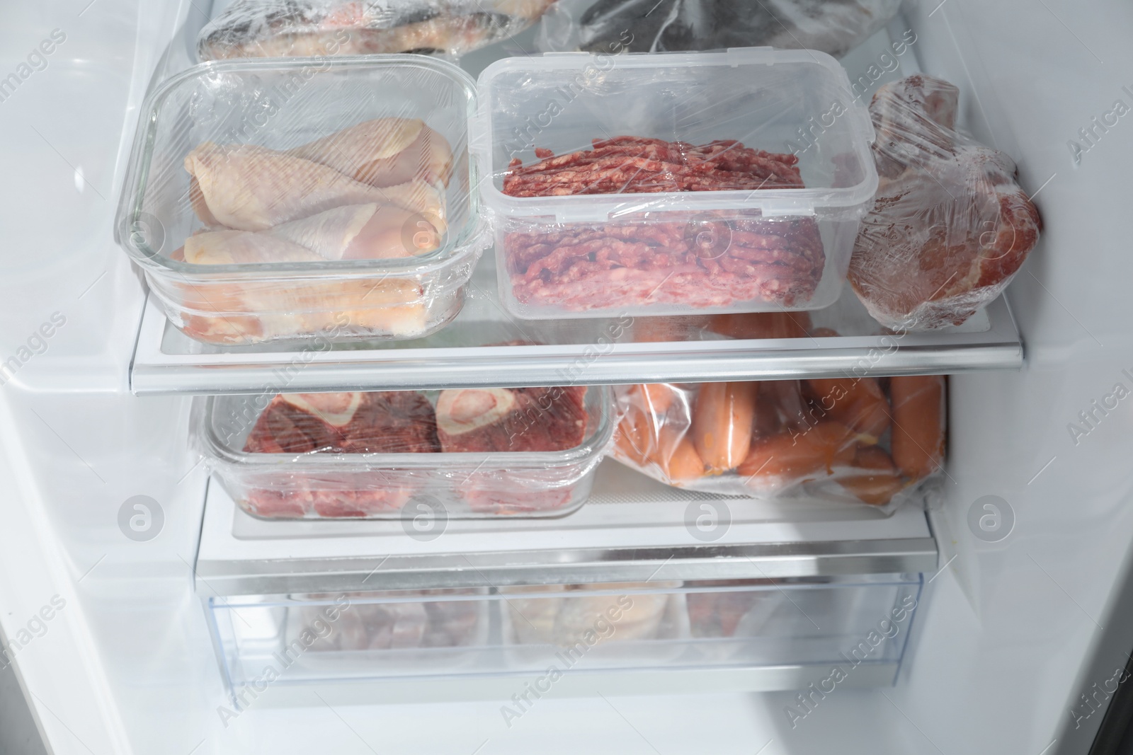 Photo of Different frozen meat products on shelves in fridge