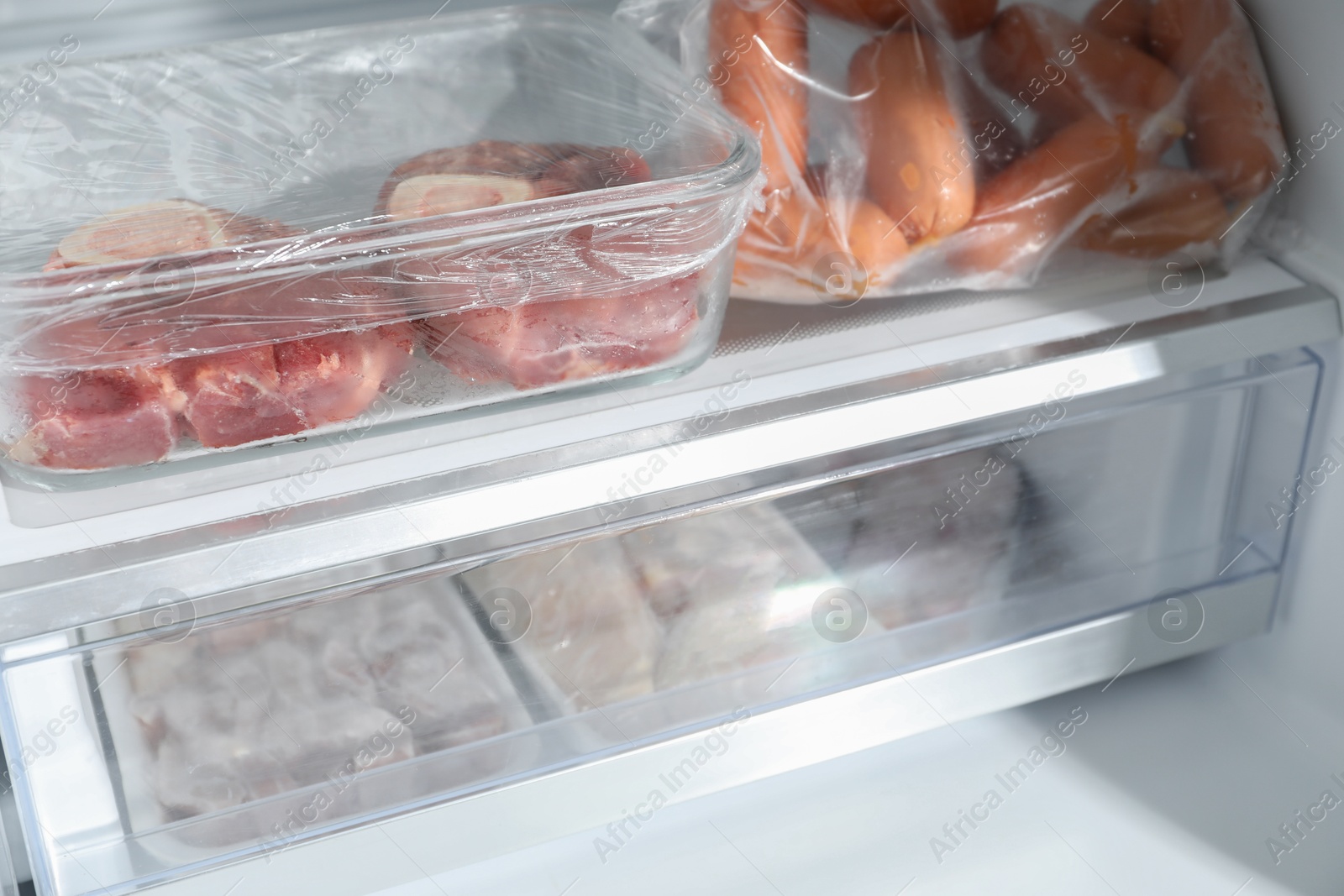 Photo of Different frozen meat products in fridge, closeup