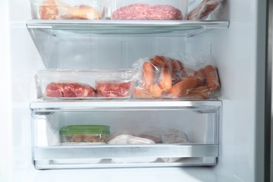 Photo of Different frozen meat products on shelves in fridge