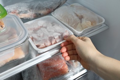 Photo of Woman taking frozen chicken meat out of fridge, closeup