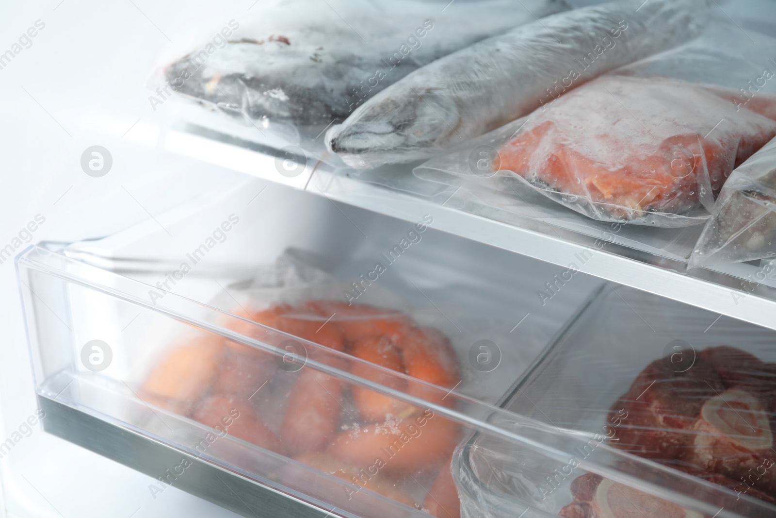 Photo of Different frozen meat and fish products in fridge, closeup