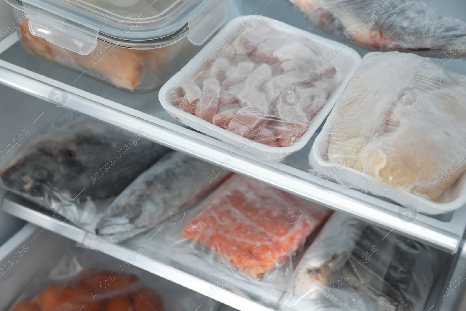 Photo of Different frozen meat and fish products in fridge, closeup