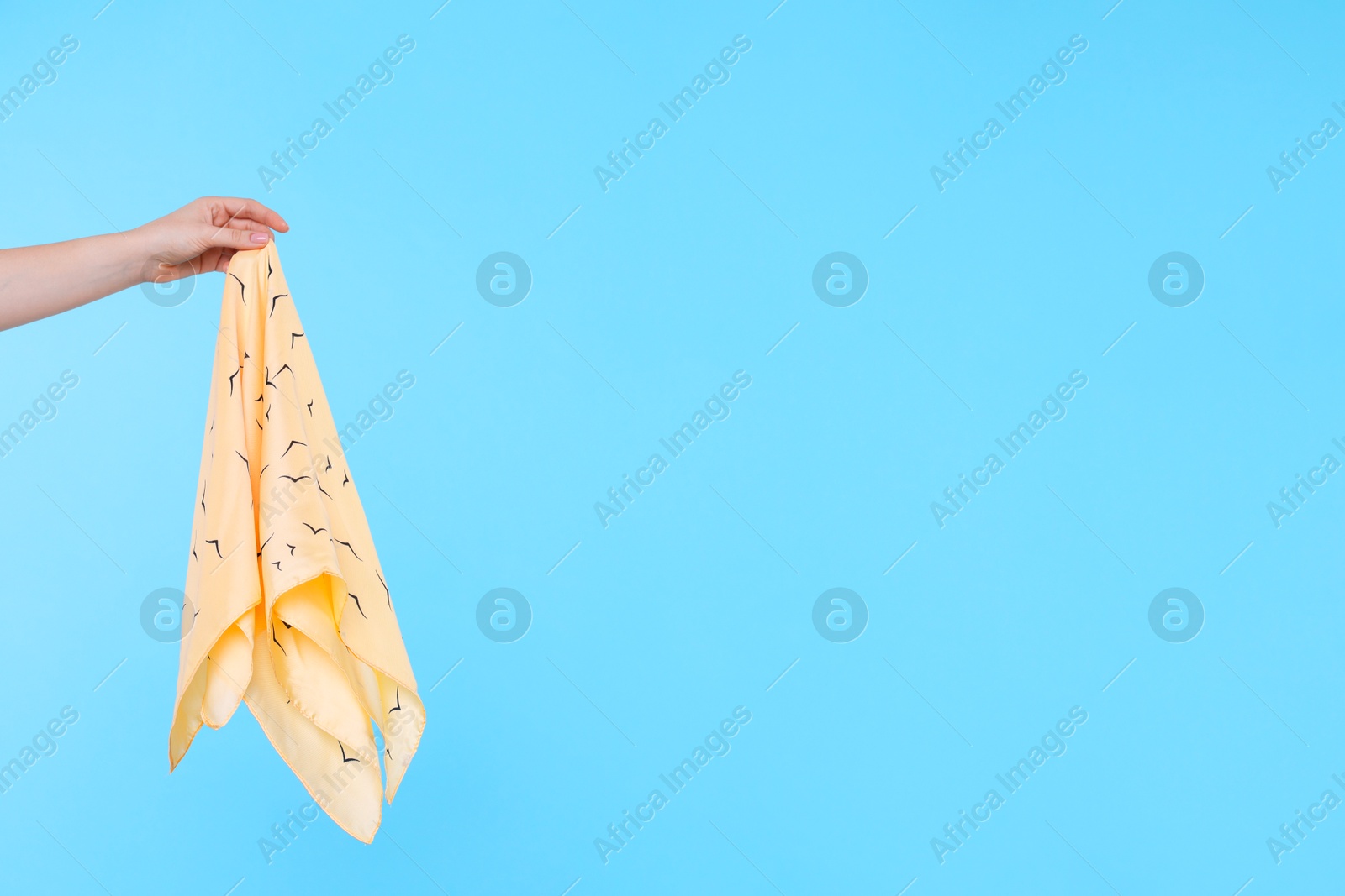 Photo of Woman holding handkerchief on light blue background, closeup. Space for text