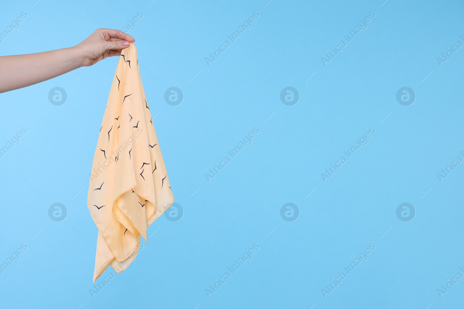 Photo of Woman holding handkerchief on light blue background, closeup. Space for text