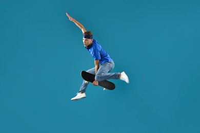 Man jumping with skateboard on light blue background