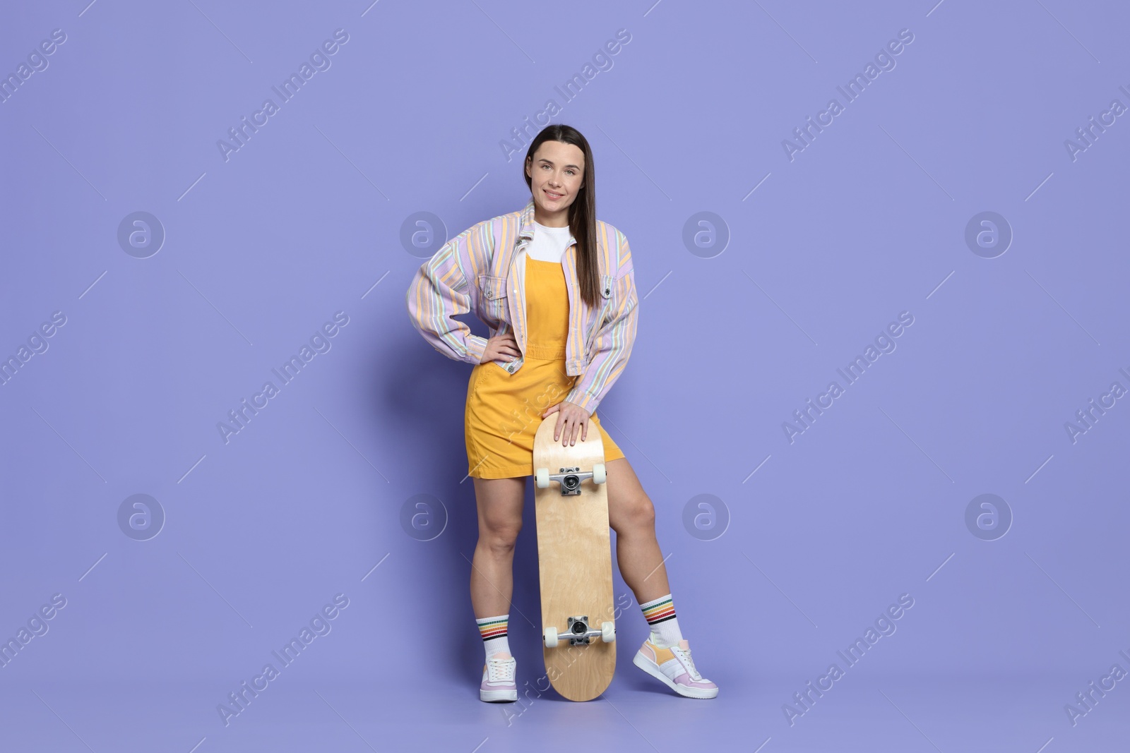 Photo of Smiling woman with skateboard on violet background