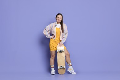 Smiling woman with skateboard on violet background