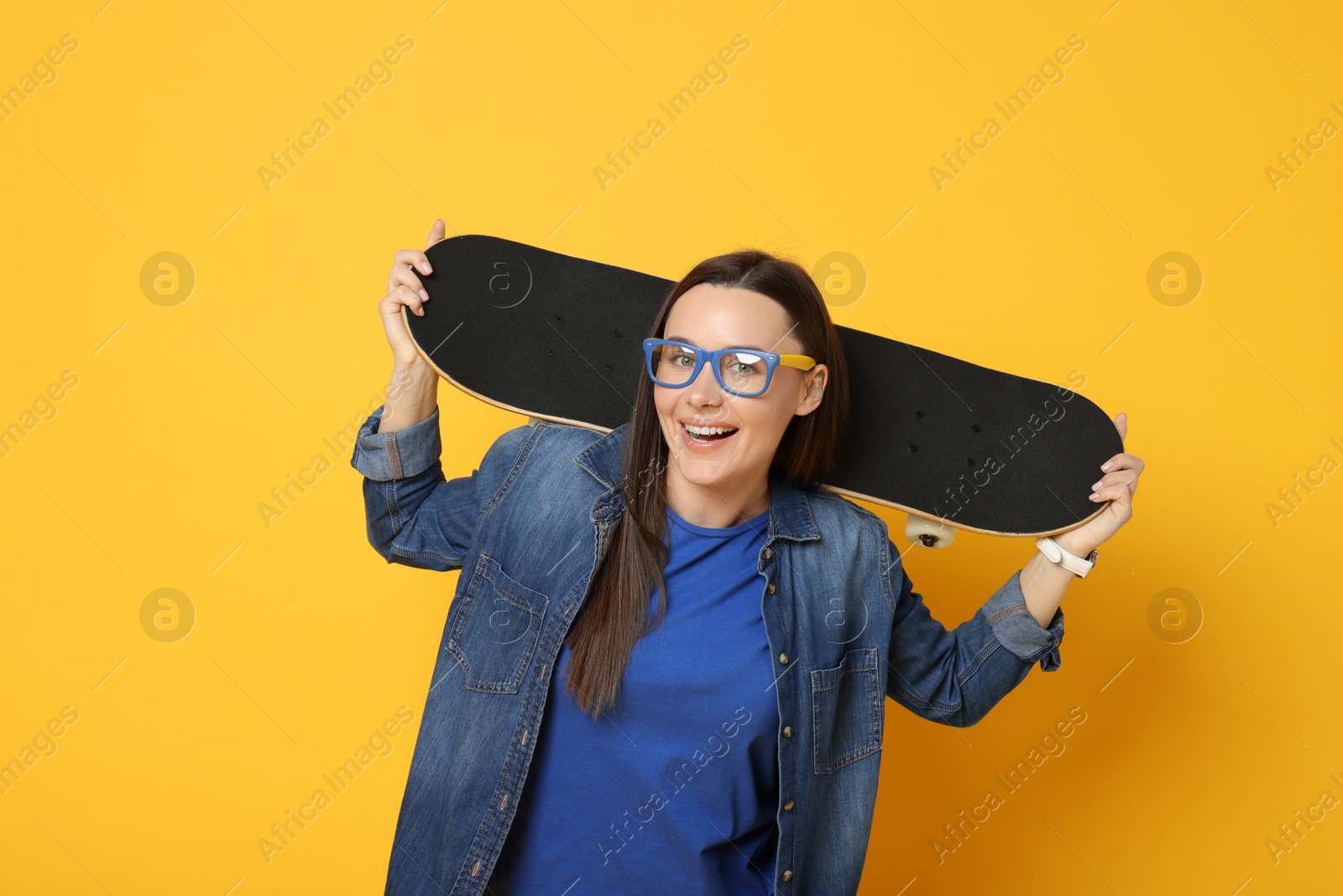 Photo of Smiling woman with skateboard on orange background