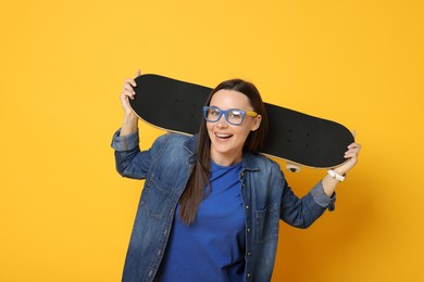 Photo of Smiling woman with skateboard on orange background