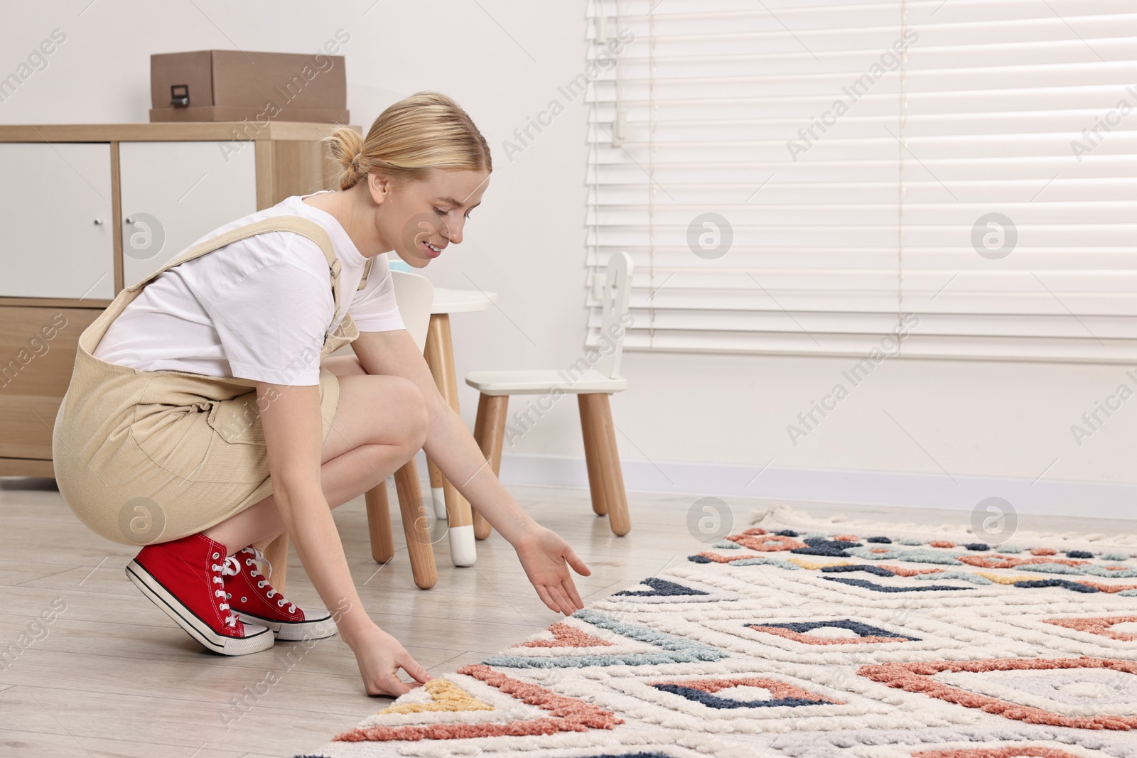 Photo of Happy decorator placing carpet in child's room. Space for text