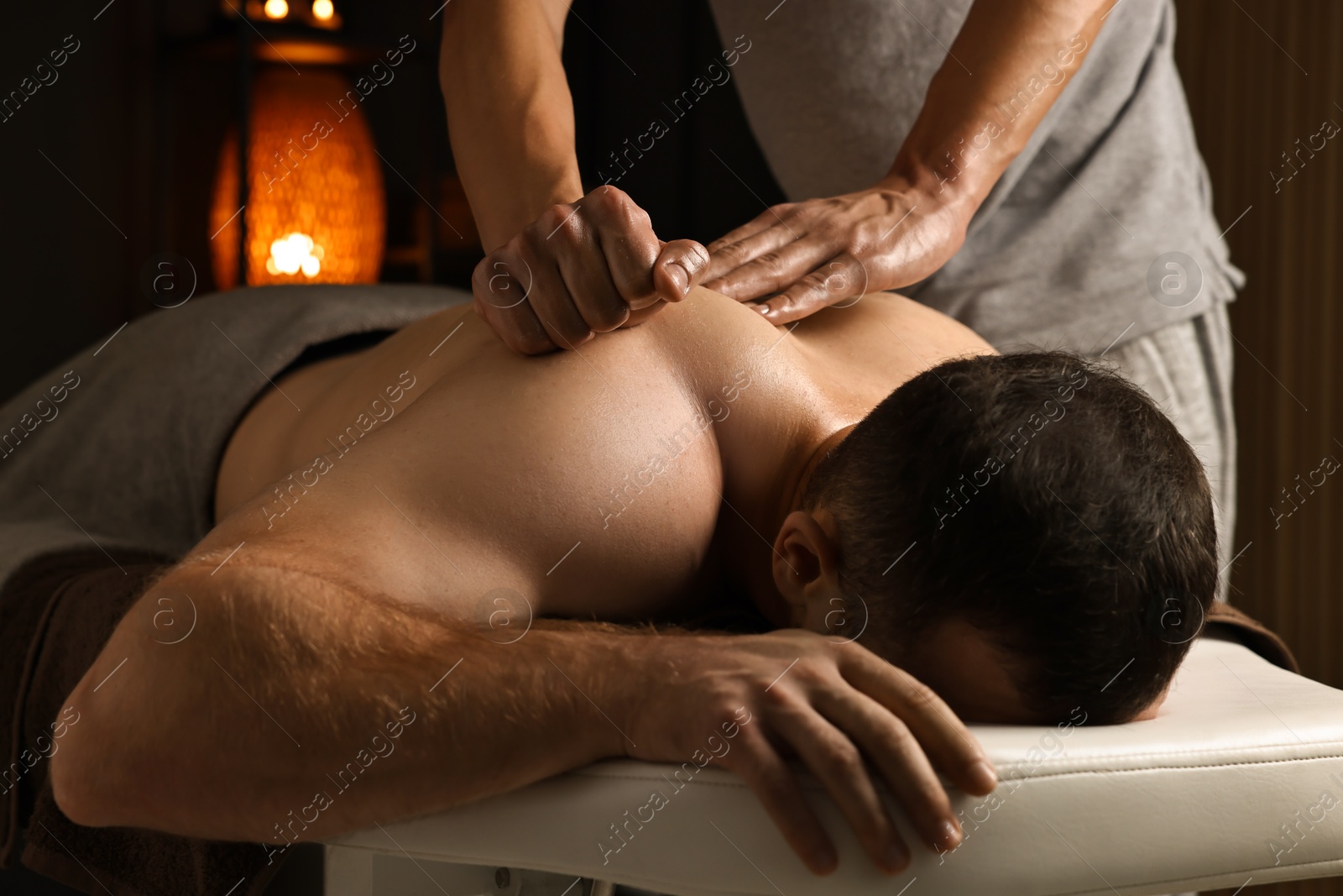 Photo of Professional physiotherapist doing shoulder massage for his client indoors, closeup